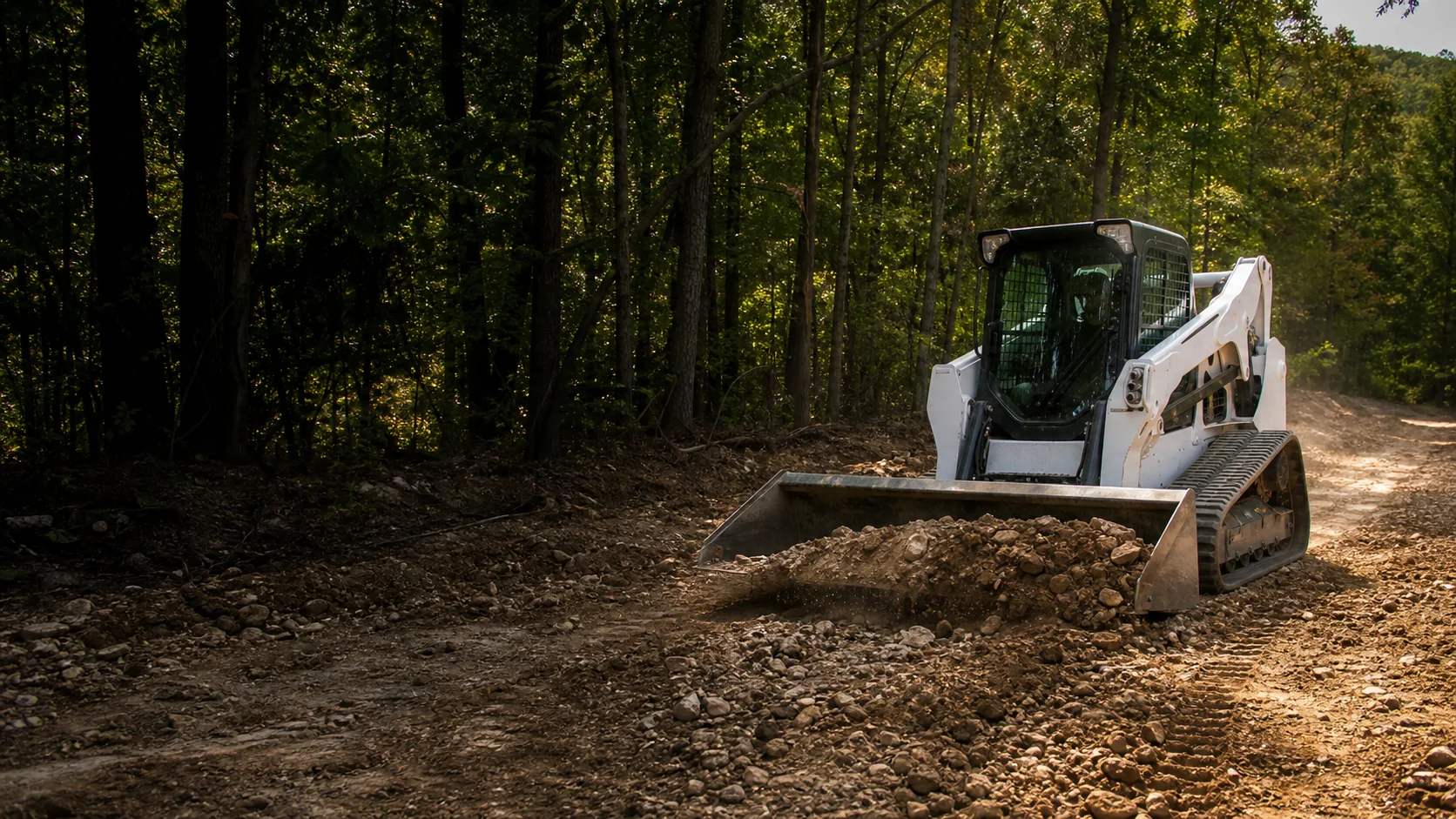 Representative wooded site-work scene with a compact tracked loader; not Calder Peak equipment or project photography